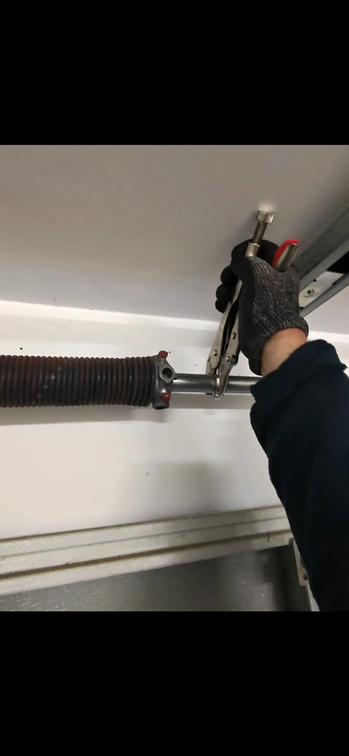 Technician adjusting a garage door torsion spring during a reliability inspection